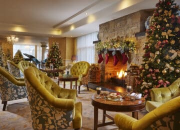 Cozy hotel lounge with Christmas decor, warm fire, elegant seating, inviting atmosphere, perfect for a festive holiday stay.