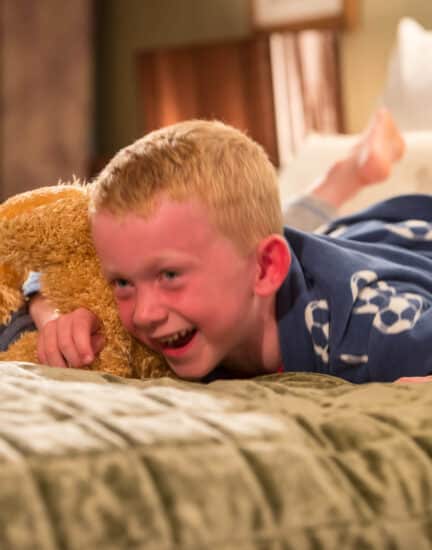 child on bed with teddy