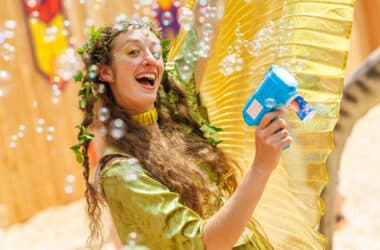 Cheerful woman in vibrant costume with bubbles in courtyard garden.