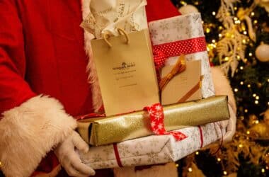 Santa holding gifts by a lit Christmas tree, showcasing Newport Hotel's festive decor and holiday experience.
