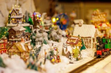 Festive winter village display with charming cottages and a miniature train, enhancing the cosy hotel lobby ambience.