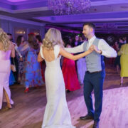Bride and groom dance together during their wedding reception at Newpark Hotel Kilkenny, surrounded by guests celebrating on a lively dance floor beneath chandeliers and colourful evening lighting.