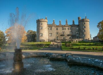 Majestic historic castle hotel with grand entrance, lush gardens, and elegant fountain, offering a luxury stay experience.