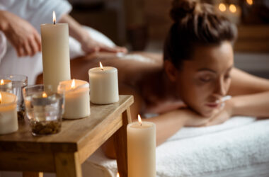 Young beautiful brunette girl relaxing in spa salon. Eyes closed. Focus on candles. Copy space.