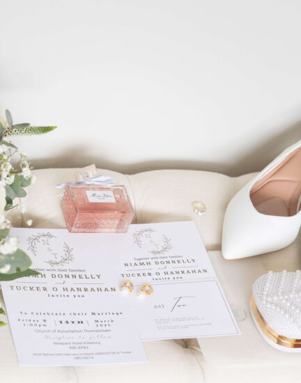Elegant wedding setup with white roses, stylish invitations, bridal shoes, and pearl clutch, showcasing hotel elegance.