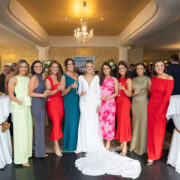 Guests celebrating in elegant hotel event hall with chandeliers, dressed in colourful evening attire, enjoying a lively atmosphere.