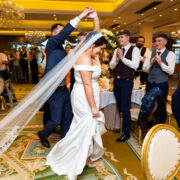 Elegant ballroom hosting lively wedding banquet with chandeliers, joyful guests, and refined decor.