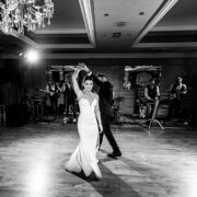 Elegant ballroom dance at hotel with live band, stunning chandelier, and spacious wooden flooring, perfect for special events.