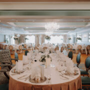 Elegant hotel dining room with chandeliers, round tables, floral centrepieces, plush chairs, ready for an upscale event.