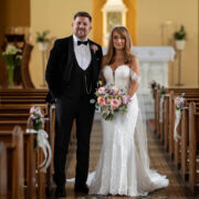 Elegant wedding couple in aisle, stunning floral decor, luxurious venue ambiance.
