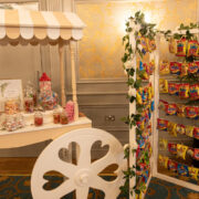 Charming sweet cart and crisps display with ornate gold walls in hotel lobby, offering complimentary treats for guests.