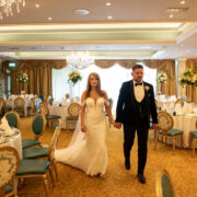 Elegant couple in grand ballroom with chandeliers, set for a wedding at luxury hotel. Experience opulence and charm.