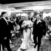 Elegant wedding ceremony in a luxurious hotel ballroom with chandeliers, filled with joyous guests and a radiant bride.