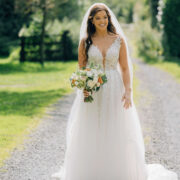 Bride in lace gown on garden path at country hotel, surrounded by greenery. Perfect wedding venue.