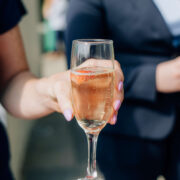 Elegant waiter offering champagne with a strawberry garnish in a stylish hotel setting.