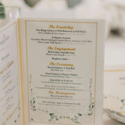 Elegant wedding menu on table, showcasing gourmet dining options and floral details in a luxurious hotel setting.