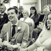 Happy couple enjoying their wedding ceremony with guests in a stylish, elegant hotel venue, featuring floral decor.