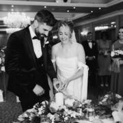 Elegant wedding ceremony at luxurious hotel ballroom with chandelier, floral decor, and happy couple lighting unity candle.