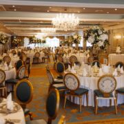 Elegant hotel ballroom with chandeliers, floral centrepieces, and luxurious seating for events and weddings.