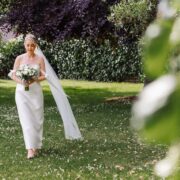 Bride walking through a lush garden with vibrant greenery, offering serene wedding venue charm.