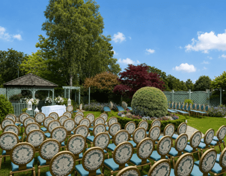 Elegant outdoor wedding venue with garden gazebo surrounded by lush greenery and floral arrangements.