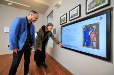 Guests explore interactive digital art display in hotel's modern gallery space, admiring vibrant, local artworks.