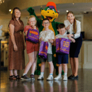 Families enjoying vibrant hotel lobby with friendly mascot and kids' activities. Welcoming atmosphere with engaging staff.