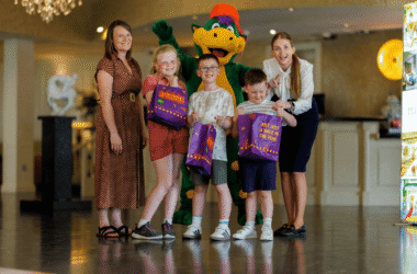 Families enjoying vibrant hotel lobby with friendly mascot and kids' activities. Welcoming atmosphere with engaging staff.