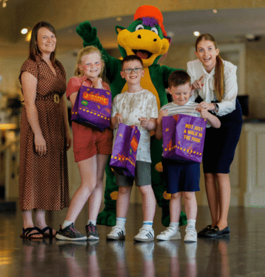 Families enjoying vibrant hotel lobby with friendly mascot and kids' activities. Welcoming atmosphere with engaging staff.