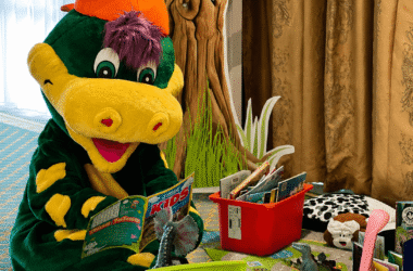 Child-friendly hotel play area with dinosaur mascot, colourful chairs, books, and toys for a fun family stay.