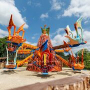 Colourful dragon-themed ride at hotel park with blue skies and lush greenery, perfect for family fun and adventure.