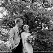 Couple enjoying wedding in lush garden, elegant hotel backdrop, romantic outdoor ceremony venue.