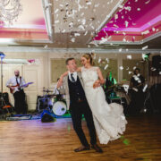 Guests enjoying a lively wedding celebration in the elegant ballroom with live band and confetti, perfect for special events.