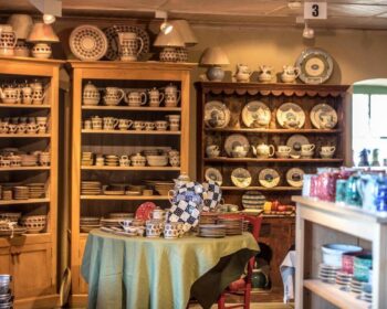 Charming pottery display room with rustic wooden shelves and handcrafted ceramics, offering a cosy, artistic hotel experience.