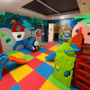 Bright, colourful children's playroom with play structures and soft flooring, perfect for family-friendly hotel stays.