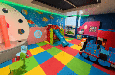 Vibrant kids' playroom with colourful slides, activity toys, and fish-themed wall at family-friendly hotel.