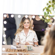 Guest enjoys a relaxing morning with coffee in a cosy hotel suite featuring a luxurious vanity mirror.