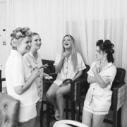Group of women in pyjamas laughing together in a cosy hotel lounge, showcasing a relaxing and friendly atmosphere.