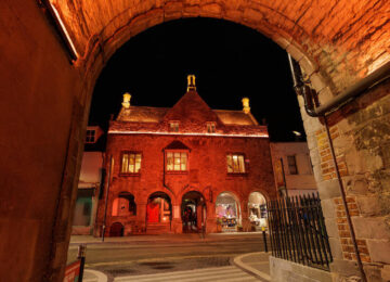 Historic hotel facade lit warmly at night, welcoming ambience near city attractions.